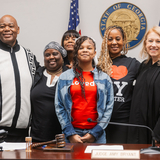 Mother and daughter gather at adoption day with loved ones and judge.